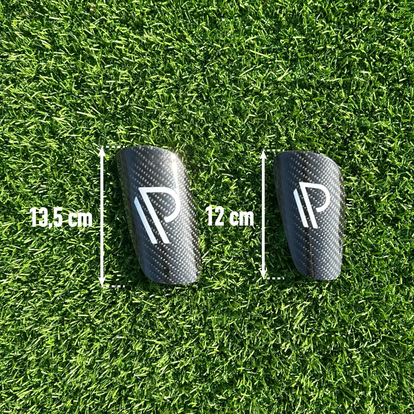 Pronto Sport carbon fiber benskinner med mål 13,5 cm og 12 cm på kunstgræs.